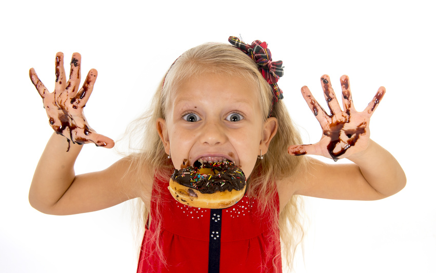 pretty little female child with long blond hair and blue eyes wearing red dress bitting donut mouth showing dirty hands